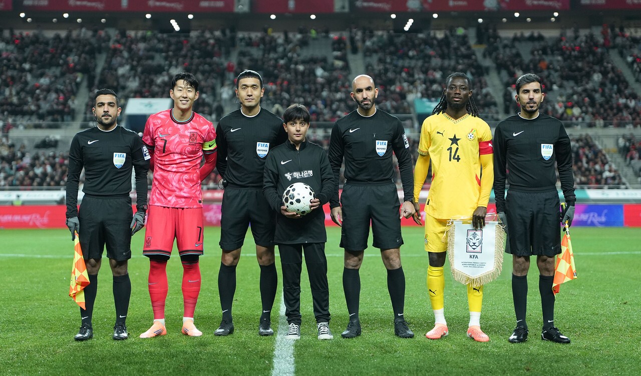 하나은행은 지난 18일 서울월드컵경기장에서 열린 대한민국과 가나의 축구 국가대표팀 A매치 경기에서 이주배경 가정 아동·청소년들에게 '매치볼 키드'와 '기수단'으로 참여할 수 있는 특별한 체험 기회를 제공했다. 이날 경기 시작에 앞서 아프가니스탄 출신 '매치볼 키드' 마시(Masih)가 양 팀 주장 및 심판진과 함께 기념촬영을 하고 있다.